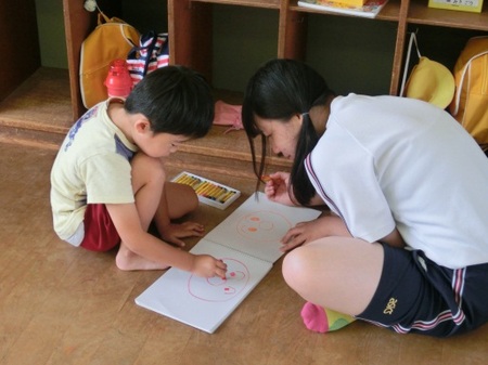 園児と床で絵を描いています