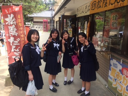 女子生徒が４人で食べ物屋さんの前にいます